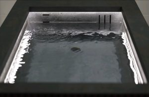 Close-up of the Ember and Ice Contrast Therapy Bath with water gently rippling in a dark stone basin and soft ambient lighting.